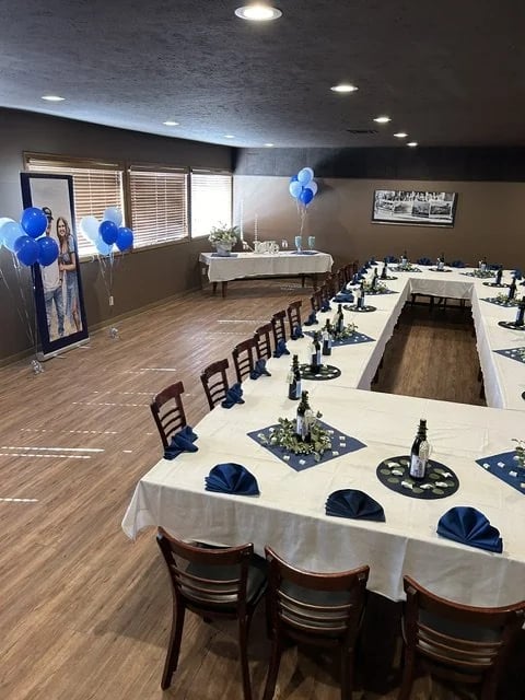 The banquet room set for a celebration with white tablecloths, navy napkins, and balloons