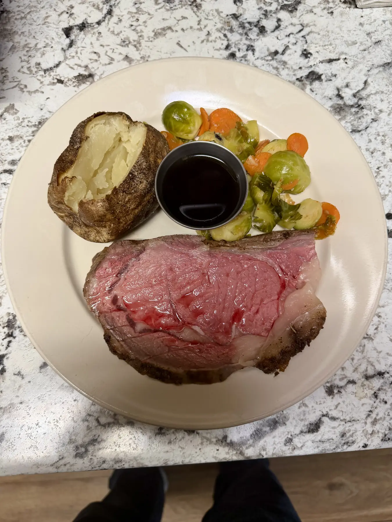 A plated slice of prime rib with mashed potatoes and vegetables